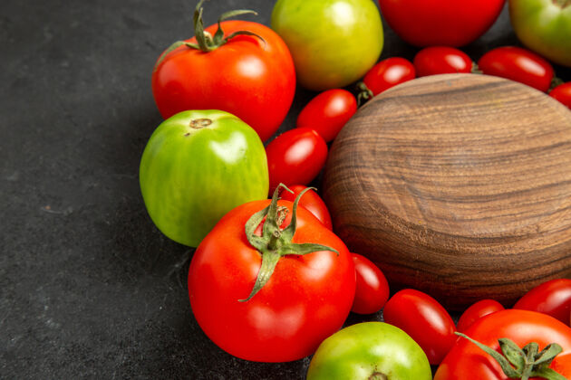 饮食底部近距离观看樱桃红和绿色的西红柿围绕在一个黑暗的背景木盘食物磨碎的底部