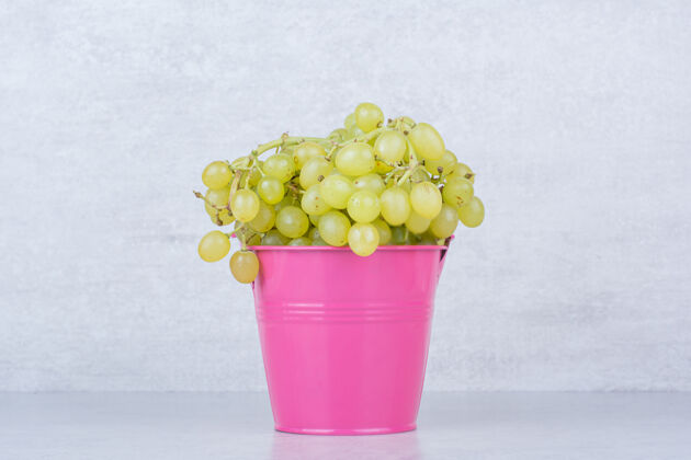 柔软一个粉红色的桶装满了绿色的甜葡萄葡萄桶装粉色