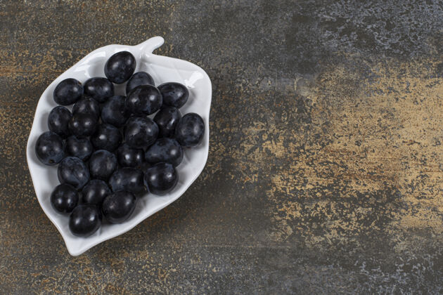 水果一束黑葡萄放在叶子形状的盘子里可口有机食品