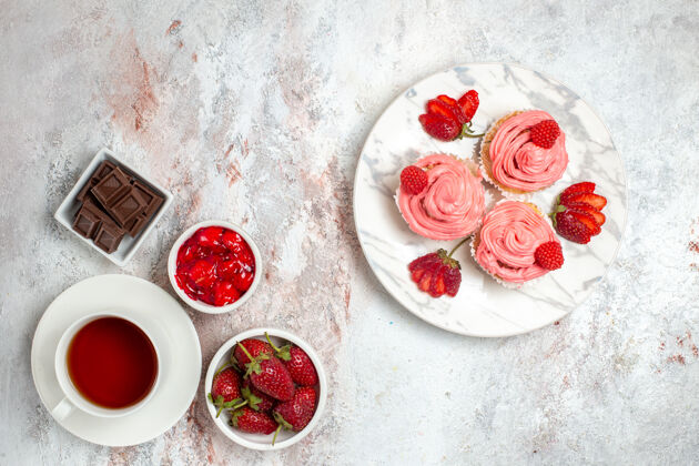 新鲜粉红色草莓蛋糕的顶视图 白色表面上有奶油和一杯茶桌子水果晚餐