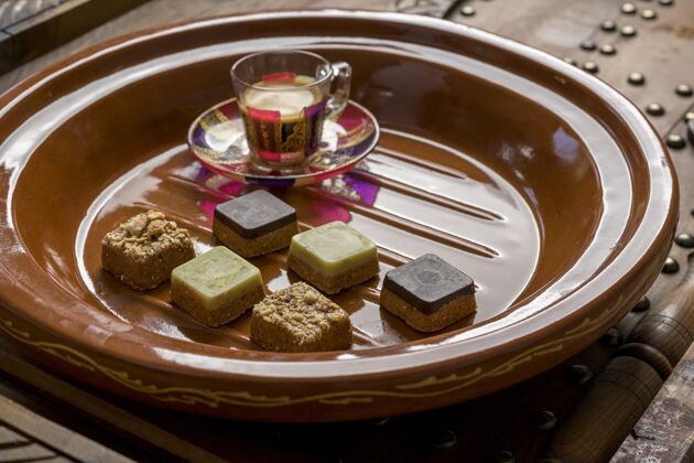 烘焙特写镜头不同类型的方形糖果与茶在一个木制托盘陶器切片咖啡馆