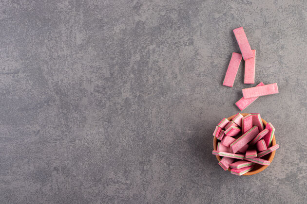 背景石桌上放着一碗长长的粉红色嚼棒糖零食五颜六色