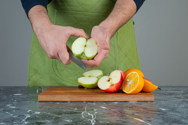 厨师男性手切青苹果大理石桌上苹果围裙准备