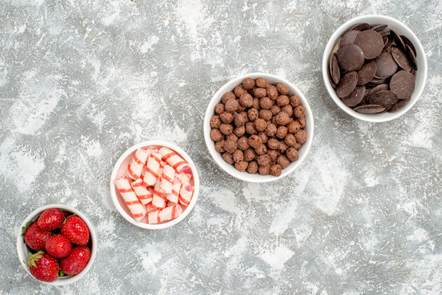 食物顶视图斜排碗草莓糖果麦片巧克力灰白色地面胡椒粉香料干