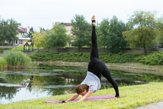 成人年轻漂亮的女人在绿色公园做瑜伽练习新鲜手莲花