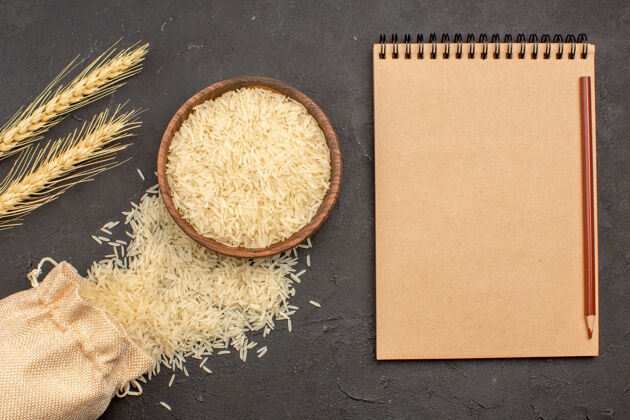 板子在灰色表面上的棕色盘子里的生大米俯视图米饭烹饪记事本