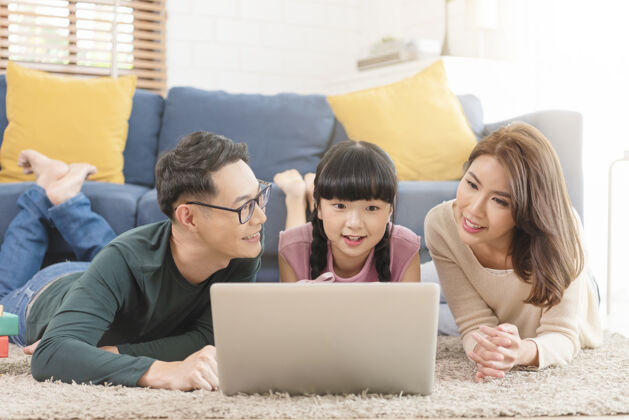 在一起快乐的亚洲家庭一起在家客厅的沙发上使用笔记本电脑父母女性亚洲人