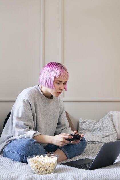 乐趣粉红色头发的女人在玩笔记本电脑上的操纵杆技术技术玩家