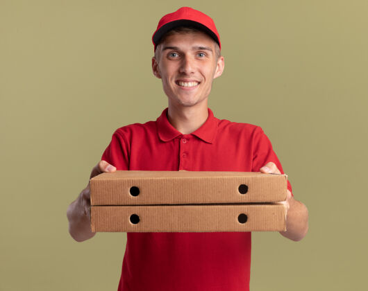 拿着微笑的年轻金发送货员拿着橄榄绿的比萨饼盒绿色年轻金发
