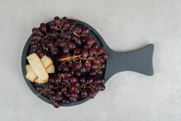 切片新鲜的红葡萄和奶酪片放在深色的木板上新鲜一餐有机
