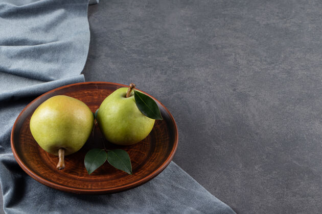 梨两个梨放在一块木板上 一块布放在大理石表面丰盛成熟农业
