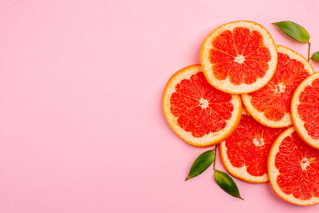 醇香粉红色表面上美味的葡萄柚和多汁的水果片的俯视图地方切片可食用水果