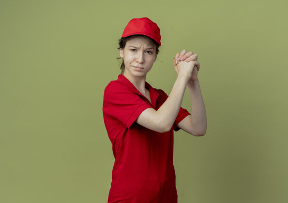 制服自信的年轻漂亮的送货女孩 穿着红色制服 戴着帽子 在橄榄绿的背景下 用复印件隔开女孩手势漂亮