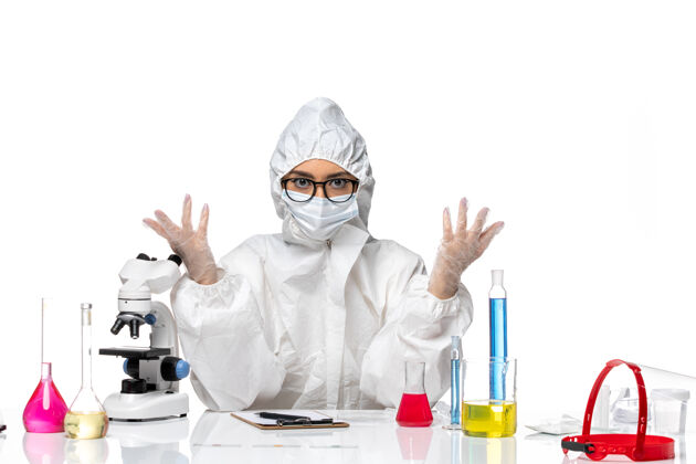 白人前视图穿着特殊防护服的女化学家坐在白色背景上解决化学冠状病毒大流行防护化学实验室外套
