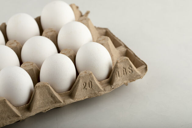开放生鸡蛋放在蛋盒里 放在白色的表面上生的蛋白质有机食品