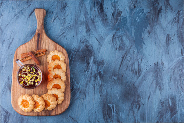 饼干蓝色背景上有果冻饼干和一杯茶的木板背景果冻烘焙