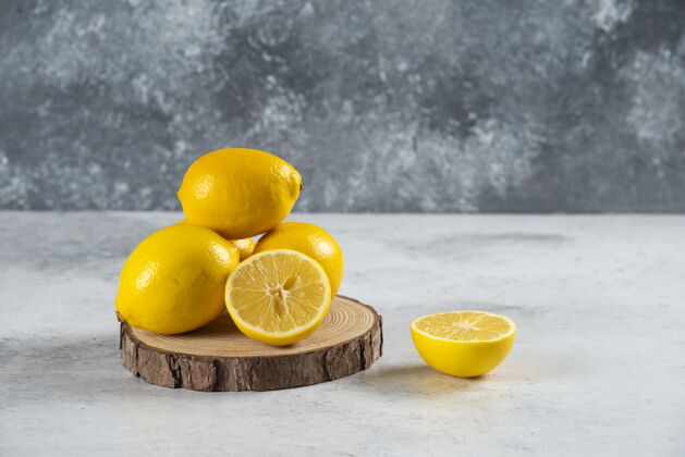 部分柠檬片放在木板上 整个柠檬放在大理石背景上新鲜多汁整个柠檬