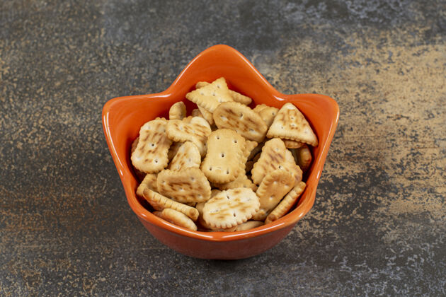 椒盐卷饼各种形状的咸饼干在橙色的碗地方咸的饼干