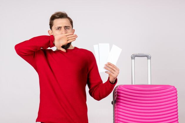 年轻男性正面图：年轻男性 带着粉色包 手持白墙彩色旅游度假机票风景游客成人
