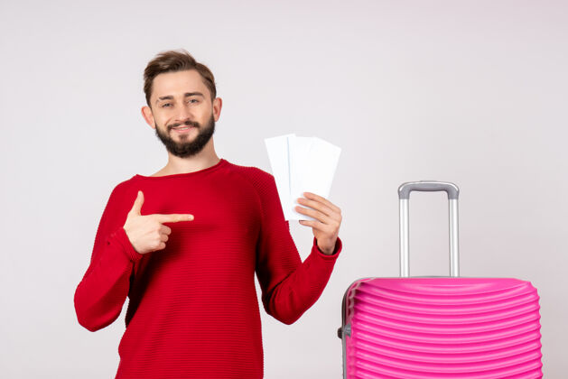航班正面图：年轻男性 带着粉色包 手持白墙彩色度假机票 远航游客男人肖像漂亮