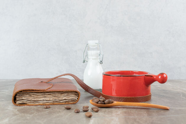 杯子咖啡杯 咖啡豆和笔记本放在大理石桌上笔记本马克杯热的