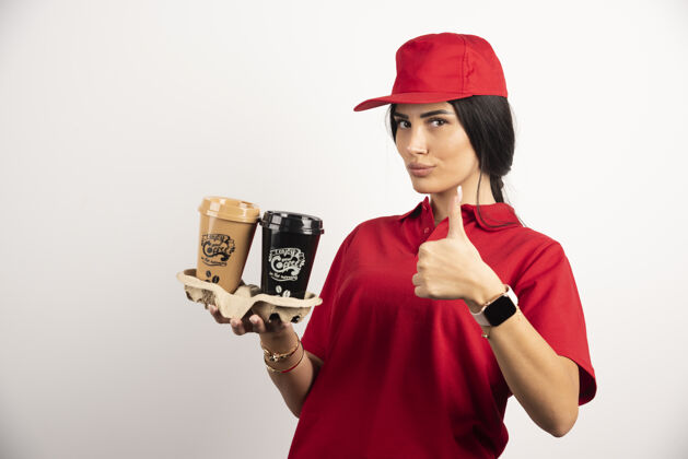 女穿着制服的女快递员拿着咖啡 竖起大拇指高质量的照片送货员快递外卖