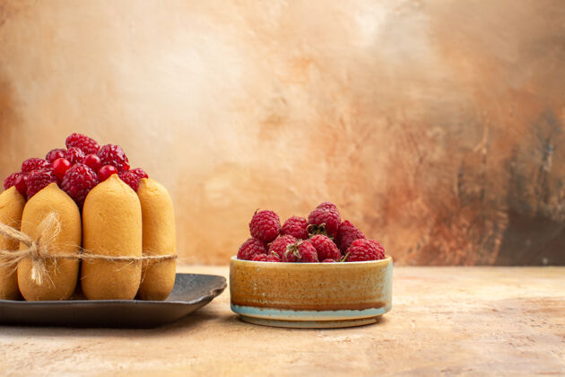 覆盆子配有礼品蛋糕和水果的餐桌侧视图 供客人在混色桌上享用壁板草莓水果