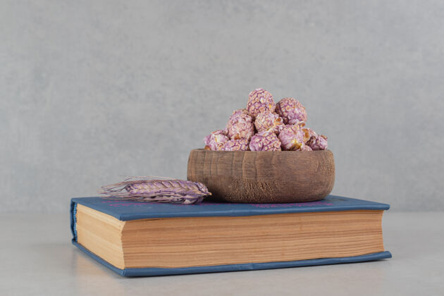 阅读在大理石背景的书上放一碗有香味的爆米花和一根紫色的麦秆背景玉米谷类