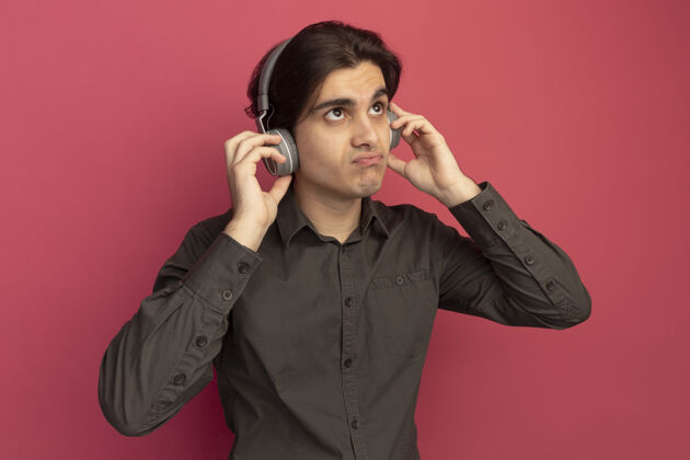 耳机一个年轻帅哥 穿着黑色t恤 头戴耳机 面不改色地站在粉红色的墙上小伙子穿年轻人