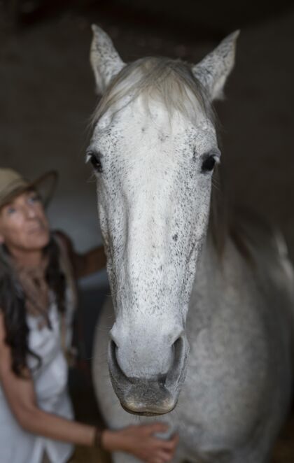 成熟女农夫和她的马的正视图牧场马庄园