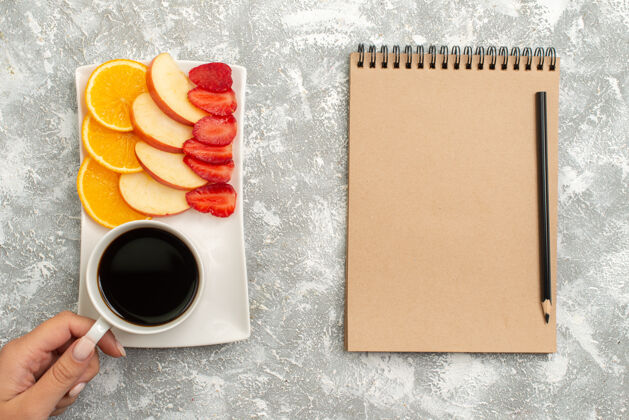 醇香俯瞰一杯咖啡 配记事本切片苹果 橙子和草莓 背景为白色水果 成熟新鲜醇厚杯子空白新鲜