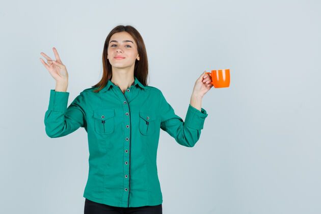 成人年轻的女士拿着一杯桔黄色的茶 一边展示着身着衬衫的三号人物 脸上洋溢着喜悦的神情 前视图人焦点女士