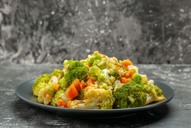 叉子特写镜头健康餐与花椰菜和胡萝卜在一个黑色的盘子与刀叉菜肴蘸酱胡萝卜