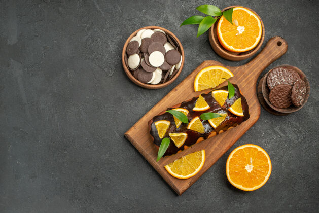 开销俯瞰图美味的蛋糕切橘子饼干在砧板上的黑桌子饼干美食午餐