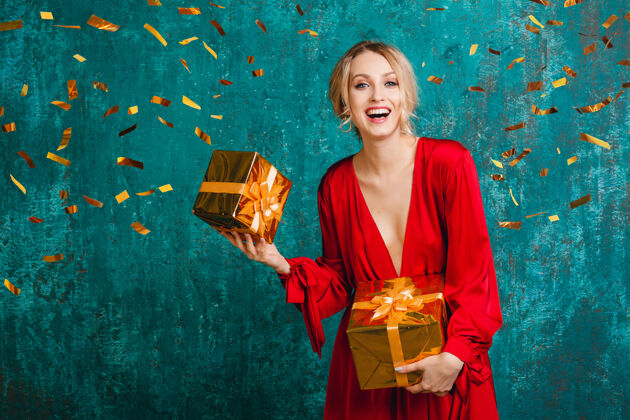 时尚迷人的快乐微笑的女人穿着时尚的红色连衣裙 用礼物庆祝圣诞节和新年金发欢呼聚会