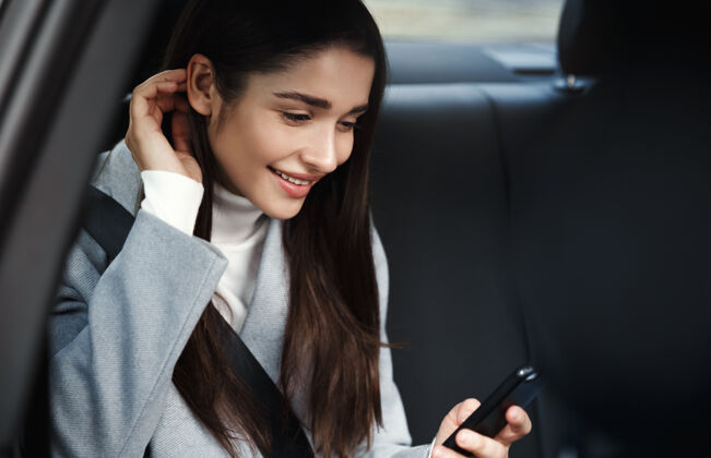 手机坐在后座上看手机短信的美女 开车时系着安全带旅游商务女性人