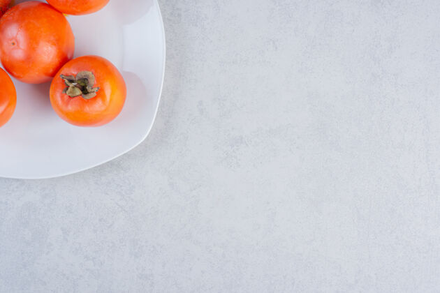 新鲜熟透的橙色柿子的特写照片在白色盘子上亚洲饮食水果