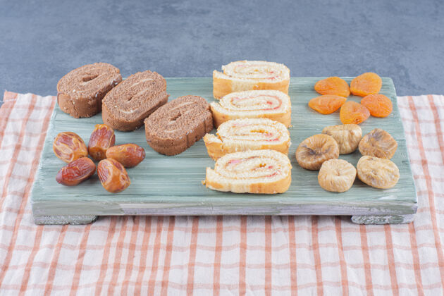 甜点把蛋糕和干果卷在木板上 放在大理石背景上卷蛋糕营养好吃的
