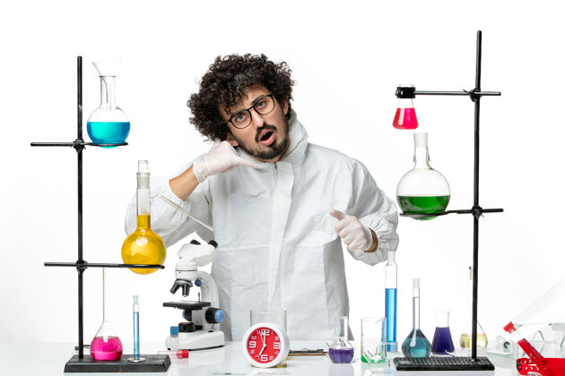 站立正面图身着特殊套装的年轻男性科学家站在桌子旁 在一个浅白的科学实验室里 拿着解决方案——传染化学实验室套装医生