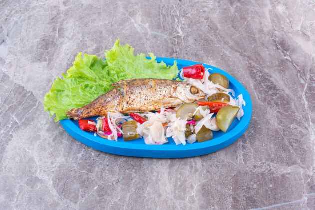 小吃把鱼和各种腌制的蔬菜放在木盘上 放在大理石上鱼黄瓜海洋