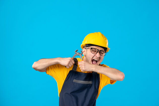 承包商身穿黄色制服的男工人正试图在蓝色上折断钳子建筑师杂工试试
