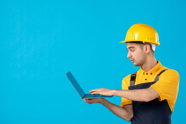 笔记本电脑穿着制服的男工人正拿着蓝色笔记本电脑工作表面工作施工