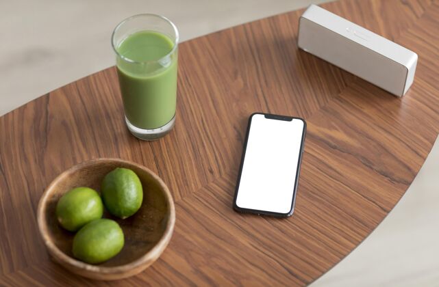 移动排毒果汁和智能手机与木桌上的空白屏幕水果热带水果美味