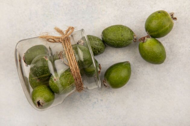 美味美味的成熟的feijoas的俯视图从一个灰色表面的玻璃罐中掉了出来成熟健康美味