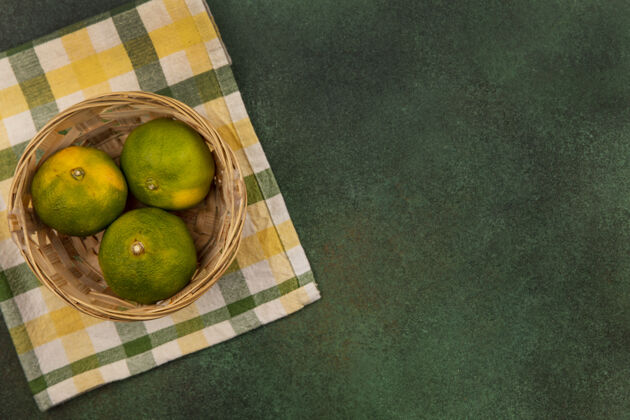毛巾顶视图复制空间橘子在一个篮子在一个黄绿色格子毛巾上的绿色墙壁格子上衣橘子