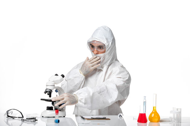 口罩正面图男性医生穿着防护服 戴着面罩 由于戴着隐形眼镜 在浅白的空间里使用显微镜专业套装病毒