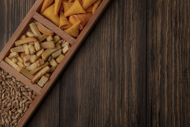 薯片顶视图圆锥形喇叭芯片上的一个木制分割板与带壳葵花籽在一个木制墙壁复制空间外壳向日葵薯片