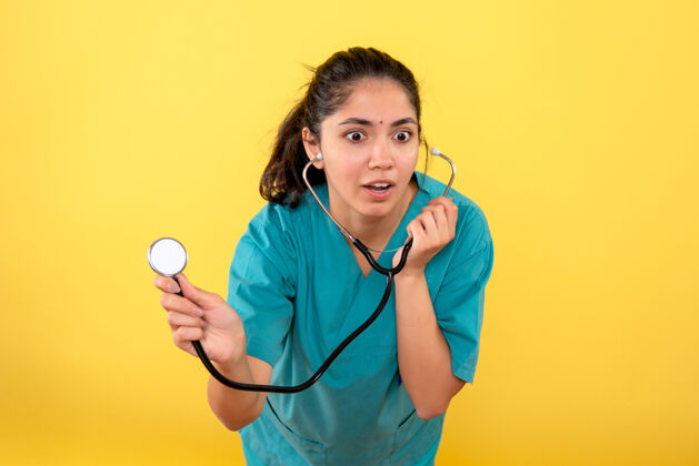 高尔夫前视图-穿着制服的女医生在黄色背景上使用听诊器制服人专业