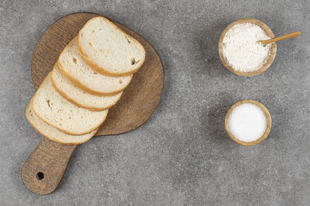 小吃用盐和面粉把白面包片放在木板上切片吐司勺子