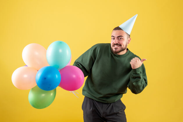 乐趣正面图黄色背景上有彩色气球的年轻男性年轻男性生日背景